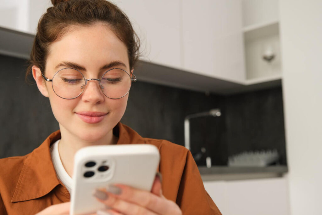 Portrait of woman in glasses using phone to order contacts